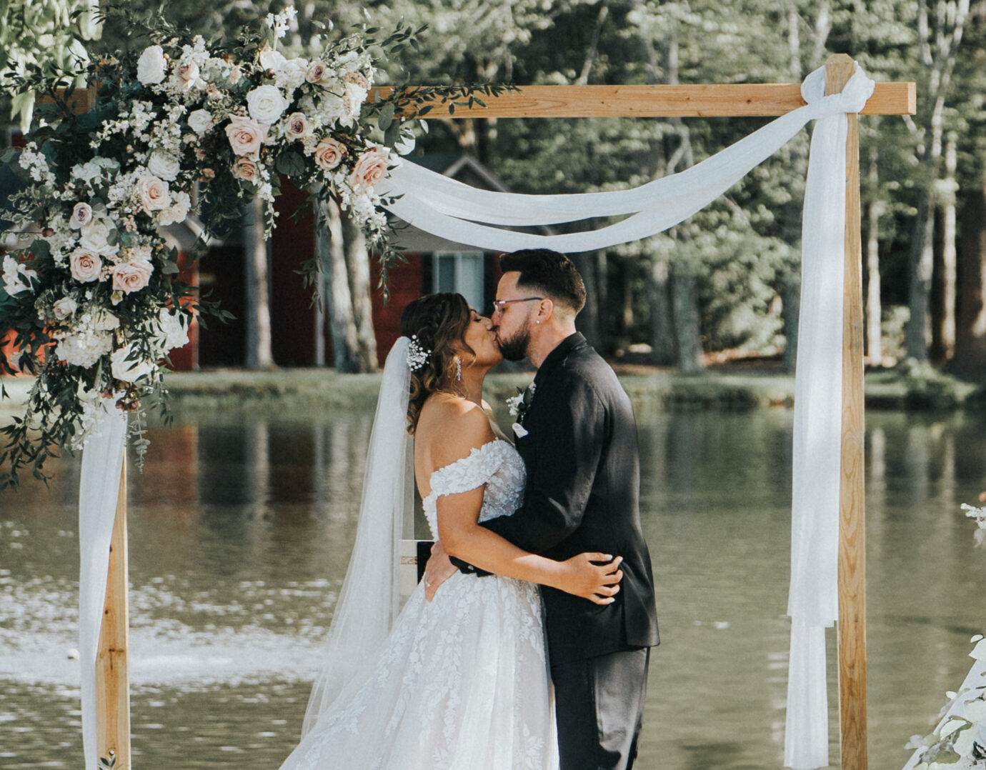Wedding couple with arbor and lake in the background at Poconos wedding venue