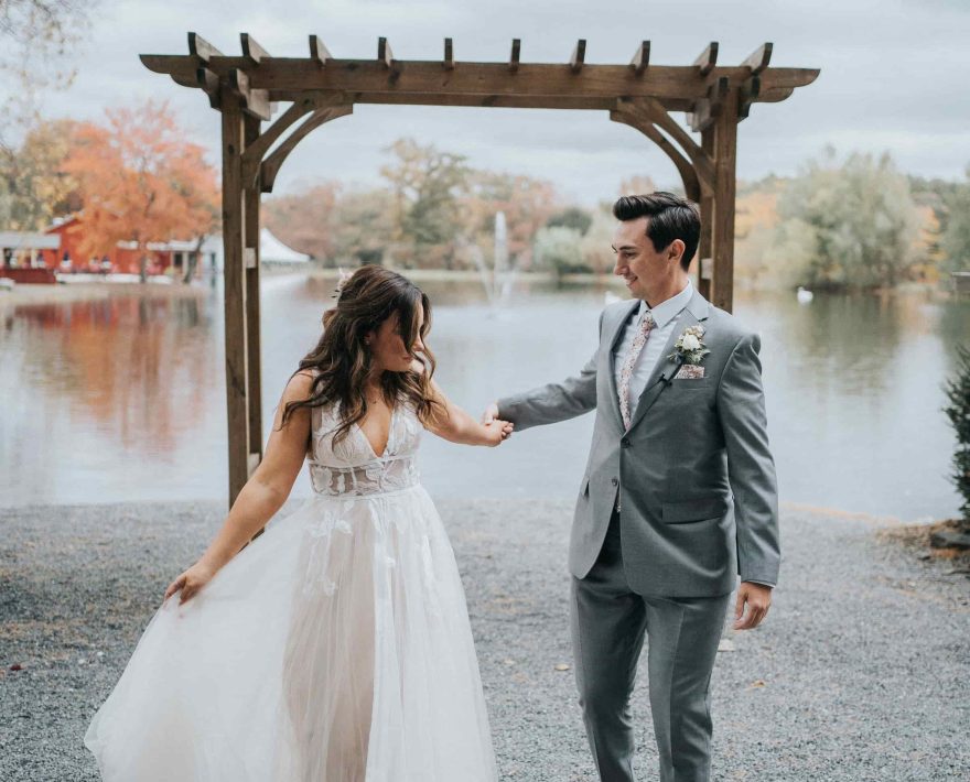 Wedding couple with arbor and lake in the background at Poconos wedding venue