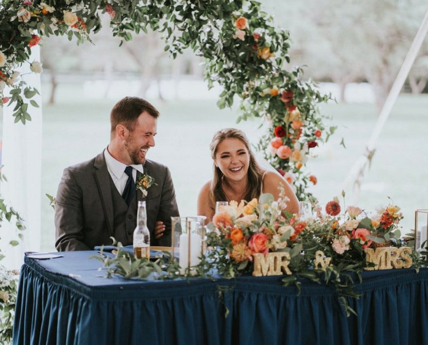 Smiling couple at wedding head table with Mr & Mrs sign