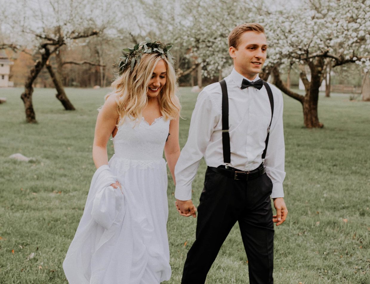 Newlywed couple walking through spring orchard in the Poconos
