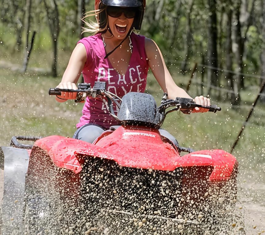 Excited happy woman on ATV ride in the Poconos going through the mud