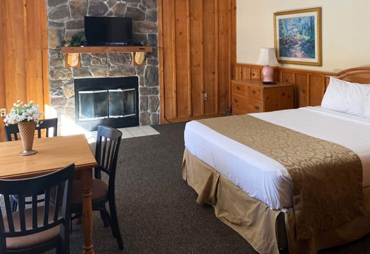 Cabin interior with king bed, fireplace, and dining table
