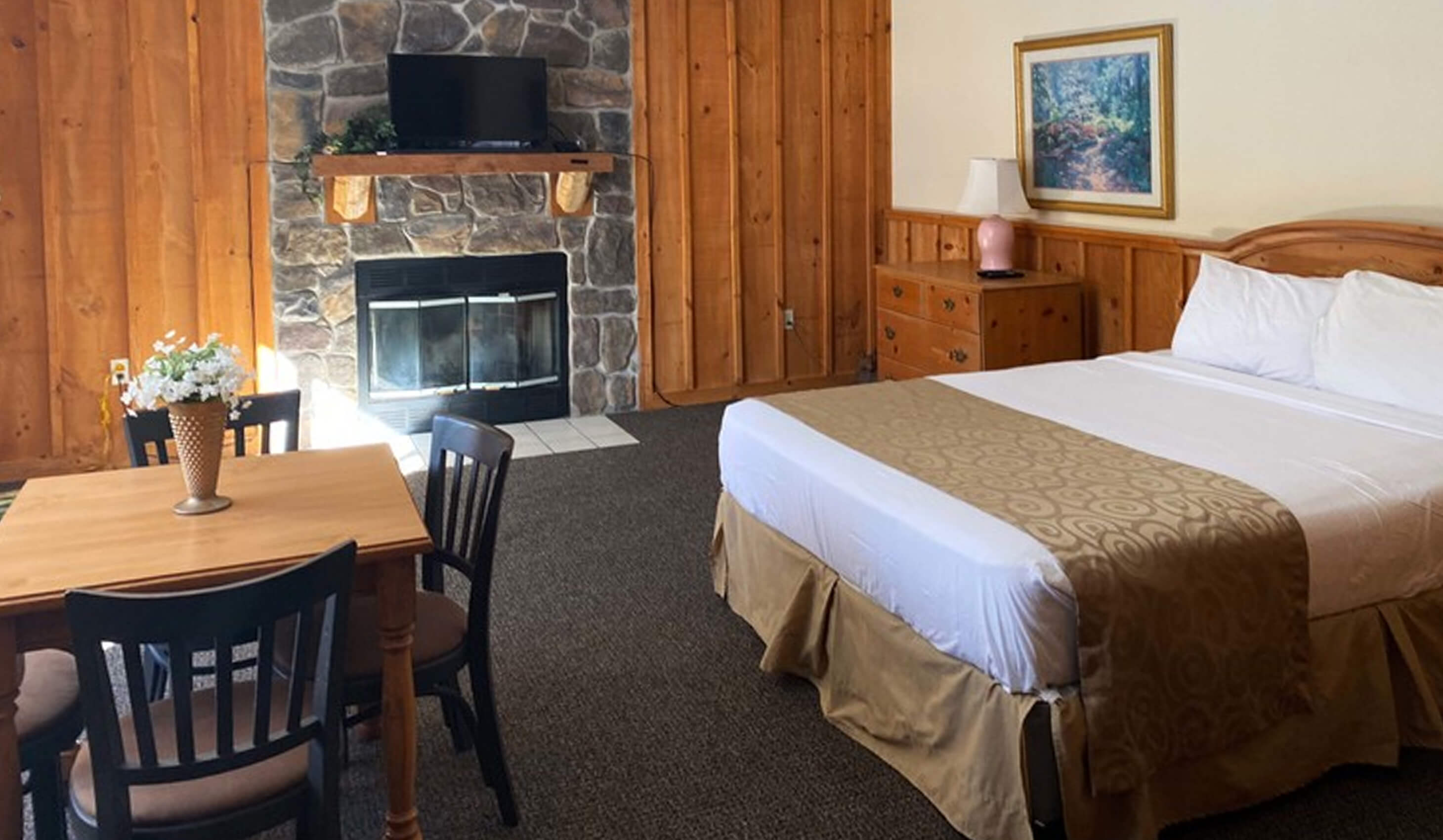 Cabin interior with king bed, fireplace, and dining table